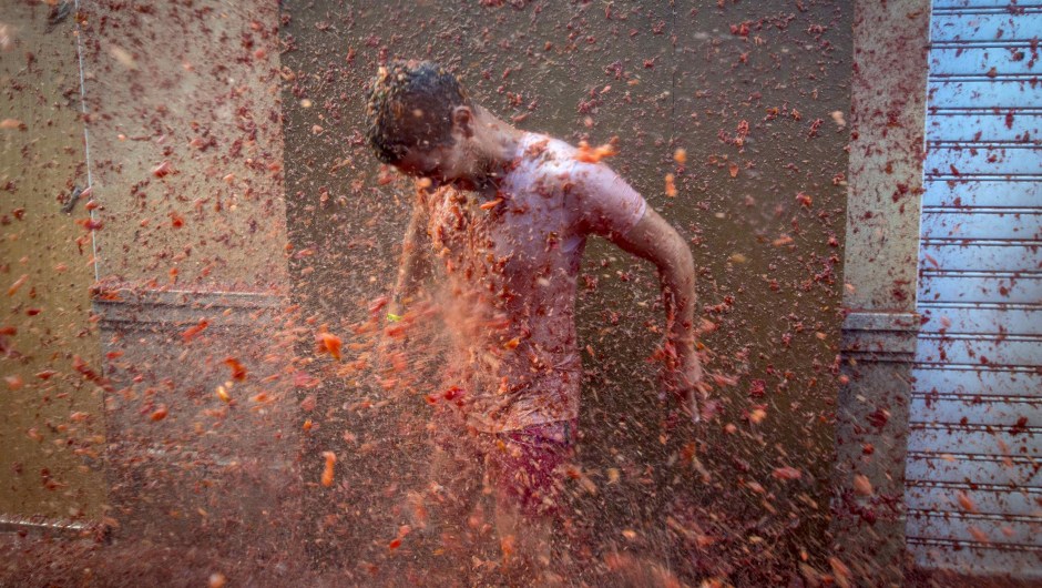 A reveller is pelted with tomato pulp during the annual "tomatina" festivities in the village of Bunol, near Valencia on August 26, 2015. Some 22,000 revellers hurled 150 tonnes of squashed tomatoes at each other drenching the streets in red in a gigantic Spanish food fight marking the 70th annual "Tomatina" battle. AFP PHOTO / BIEL ALINO (Photo credit should read BIEL ALINO/AFP/Getty Images)