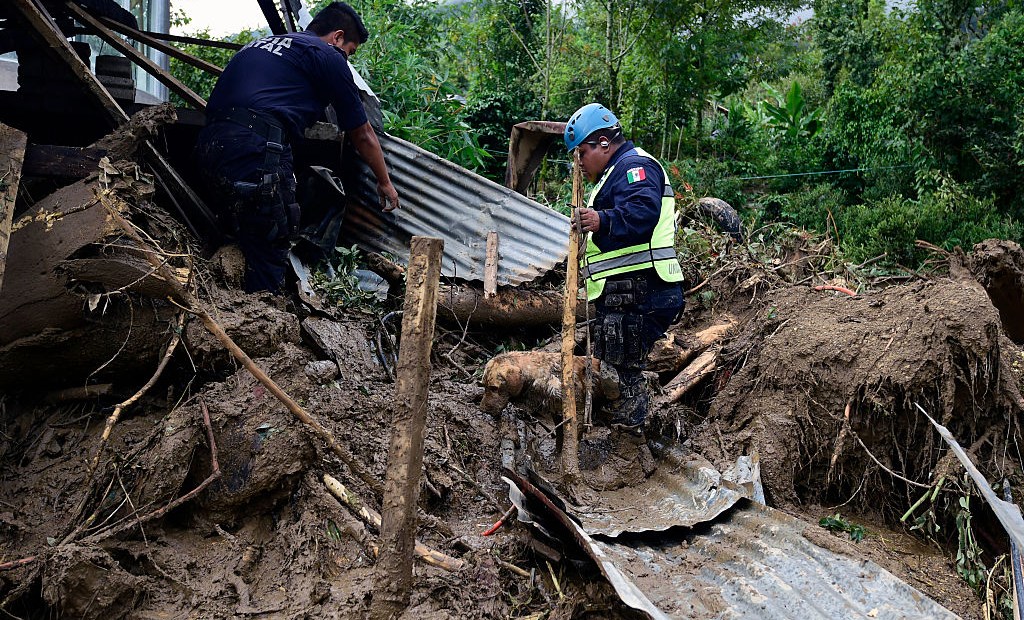 A Federal Police rescuer and his sniffer dog search for buried corpses amid the damage caused by a landslide ensuing the passage of Tropical Storm Earl in the community of Xaltepec, Puebla state, eastern Mexico on August 8, 2016. A total of 29 people died in the communities of Xaltepec, Tlaola and Huauchinango in the Mexican state of Puebla after their homes were buried by landslides following heavy rains from Earl, which reached Mexican territory on Thursday as a tropical storm and Saturday was only a remnant low pressure. / AFP / AE / ALFREDO ESTRELLA (Photo credit should read ALFREDO ESTRELLA/AFP/Getty Images)