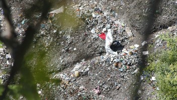 A forensic examiner searches for human remains below a garbage-strewn hillside in the densely forested mountains on the outskirts of Cocula, Mexico, on October 28, 2014. Suspects arrested earlier this week told prosecutors that many of the 43 students who disappeared on September 26 from Iguala had been held near this location. Mexico recoiled in fresh horror Tuesday over the discovery of yet another mass grave, in the futile month-long search for 43 missing college students. AFP PHOTO/ JESUS GUERRERO (Photo credit should read JESUS GUERRERO/AFP/Getty Images)
