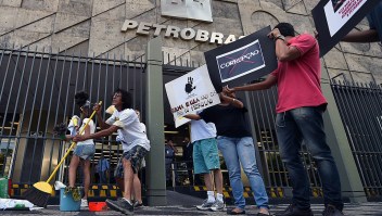 Activists hold signs during a protest against corruption outside state-owned oil giant Petrobras in Rio de Janeiro on December 16, 2014. AFP PHOTO/VANDERLEI ALMEIDA (Photo credit should read VANDERLEI ALMEIDA/AFP/Getty Images)