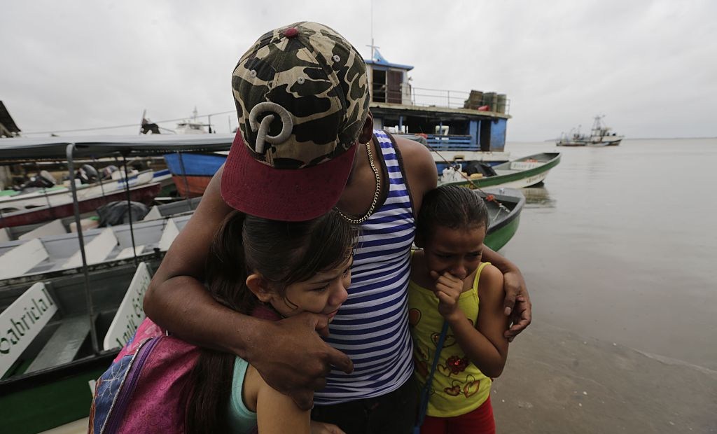 TOPSHOT - Two children seek cover under the embrace of their father before Hurricane Otto arrives in Bluefields, Nicaragua on November 23, 2016. A Caribbean storm verging on a hurricane spun towards the coasts of Costa Rica and Nicaragua on Wednesday, prompting evacuations and red alerts ahead of "life-threatening" flash flooding. / AFP / INTI OCON (Photo credit should read INTI OCON/AFP/Getty Images)