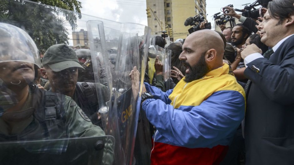 OPSHOT - CORRECTION - Venezuelan opposition deputy Marco Bozo (C) scuffles with National Guard personnel in riot gear during a protest in front of the Supreme Court in Caracas on March 30, 2017. Venezuela's Supreme Court took over legislative powers Thursday from the opposition-majority National Assembly, whose speaker accused leftist President Nicolas Maduro of staging a "coup." / AFP PHOTO / JUAN BARRETO / The erroneous mention[s] appearing in the metadata of this photo by JUAN BARRETO has been modified in AFP systems in the following manner: [Marco Bozo] instead of [Carlos Bozo]. Please immediately remove the erroneous mention[s] from all your online services and delete it (them) from your servers. If you have been authorized by AFP to distribute it (them) to third parties, please ensure that the same actions are carried out by them. Failure to promptly comply with these instructions will entail liability on your part for any continued or post notification usage. Therefore we thank you very much for all your attention and prompt action. We are sorry for the inconvenience this notification may cause and remain at your disposal for any further information you may require. (Photo credit should read JUAN BARRETO/AFP/Getty Images)