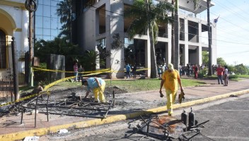 Town hall civil servants clean burnt fences outside the Congress, set on fire on the eve by demonstrators protesting against the approval of a constitutional amendment for presidential reelection in Asuncion on April 1, 2017. Paraguayan senators approved a contested law allowing President Horacio Cartes to seek reelection in 2018, prompting furious protesters to break into the legislature, ransacking lawmakers' offices and starting fires. / AFP PHOTO / NORBERTO DUARTE (Photo credit should read NORBERTO DUARTE/AFP/Getty Images)
