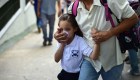 TOPSHOT - A schoolgirl covers her nose and mouth to avoid breathing tear gas shot by police at opponents of Venezuelan President Nicolas Maduro marching in Caracas on April 26, 2017. Protesters in Venezuela plan a high-risk march against President Maduro Wednesday, sparking fears of fresh violence after demonstrations that have left 26 dead in the crisis-wracked country. / AFP PHOTO / RONALDO SCHEMIDT (Photo credit should read RONALDO SCHEMIDT/AFP/Getty Images)