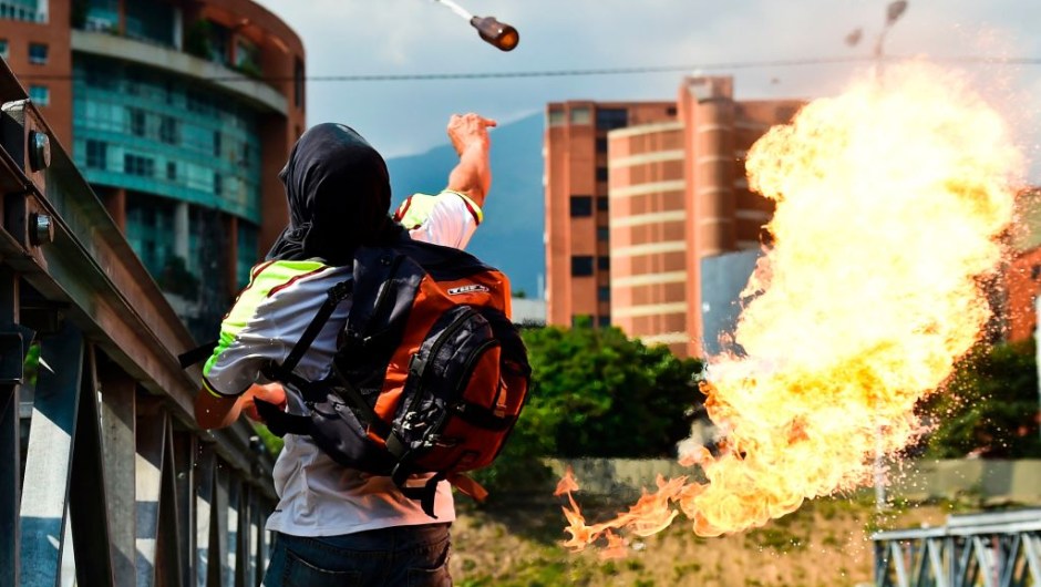 An opposition activist clashes with riot police during a protest march against President Nicolas Maduro in Caracas on April 26, 2017. Venezuelan riot police fired tear gas to stop anti-government protesters from marching on central Caracas, the latest clash in a wave of unrest that, up to now, has left 26 people dead. / AFP PHOTO / RONALDO SCHEMIDT (Photo credit should read RONALDO SCHEMIDT/AFP/Getty Images)