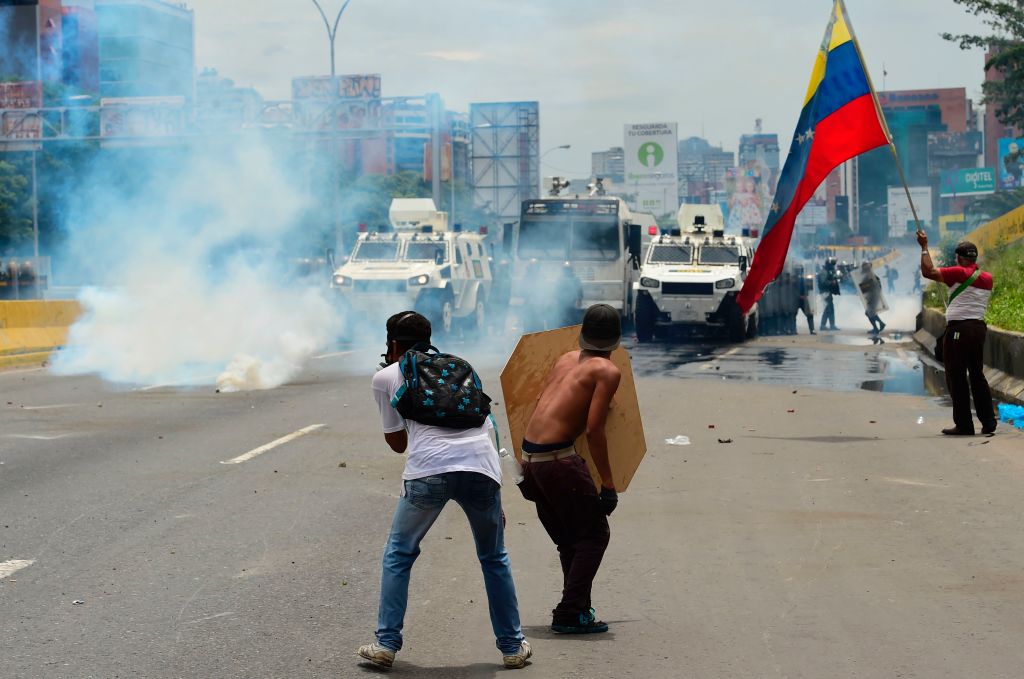 Demonstrators clash with riot police during a protest against Venezuelan President Nicolas Maduro, in Caracas on May 3, 2017. Venezuela's angry opposition rallied Wednesday vowing huge street protests against President Nicolas Maduro's plan to rewrite the constitution and accusing him of dodging elections to cling to power despite deadly unrest. / AFP PHOTO / RONALDO SCHEMIDT (Photo credit should read RONALDO SCHEMIDT/AFP/Getty Images)