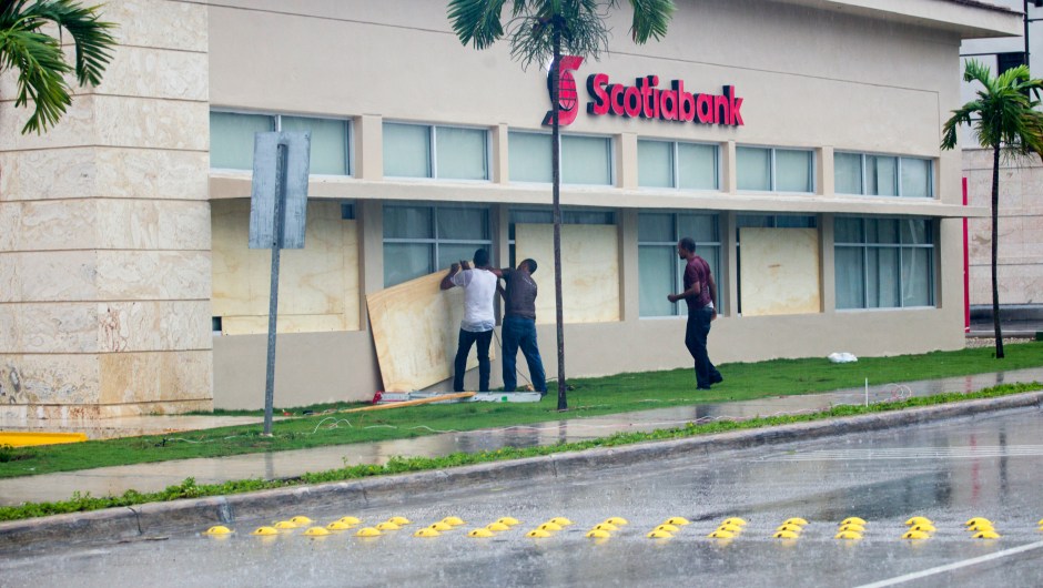 Workers cover the windows of a bank in Punta Cana, in the Dominican Republic, as Hurricane Maria approaches on September 20, 2017. The government of the Dominican Republic told people to stay home from their public and private sector jobs on Thursday, when the hurricane is expected to hit the island. / AFP PHOTO / Erika SANTELICES (Photo credit should read ERIKA SANTELICES/AFP/Getty Images)