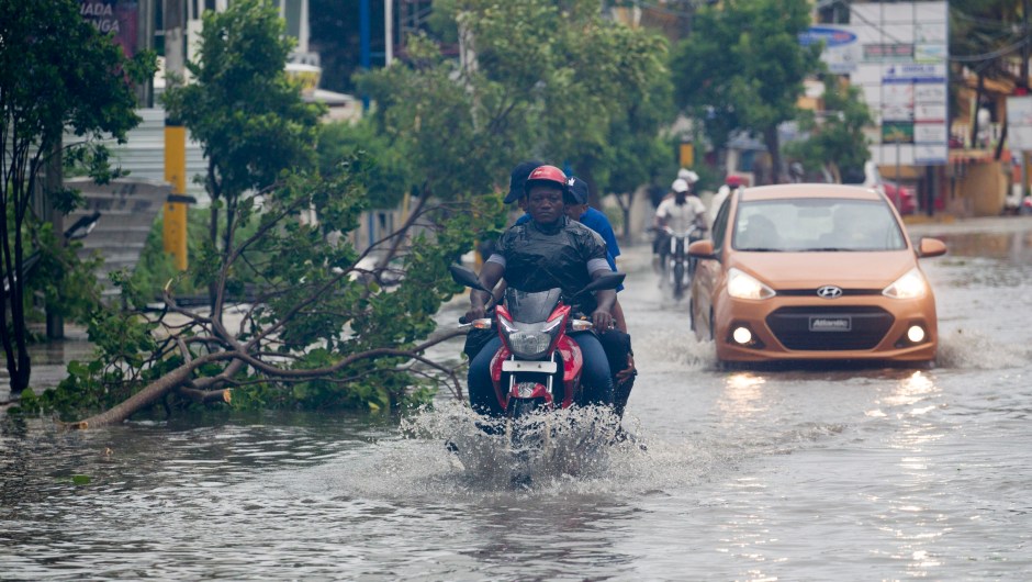 People drive along a flooded street in Punta Cana, in the Dominican Republic, as Hurricane Maria approaches on September 20, 2017. The government of the Dominican Republic told people to stay home from their public and private sector jobs on Thursday, when the hurricane is expected to hit the island. / AFP PHOTO / Erika SANTELICES (Photo credit should read ERIKA SANTELICES/AFP/Getty Images)