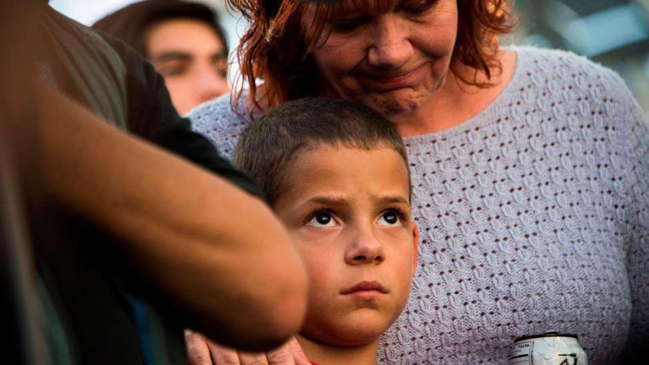 Nine-year old Alexander Wells is hugged by his grandmother at a candlelight vigil at Las Vegas City Hall October 2, 2017, after a gunman killed at least 58 people and wounded more than 500 others when he opened fire on a country music concert in Las Vegas, Nevada late October 1, 2017. Alexander had friends who were injured in another shooting recently and insisted on attending this vigil according to his family. / AFP PHOTO / Robyn Beck (Photo credit should read ROBYN BECK/AFP/Getty Images)