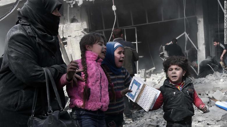 Una mujer y sus hijos corren para protegerse tras un bombardeo en Hamouria, el lunes 19 de febrero.