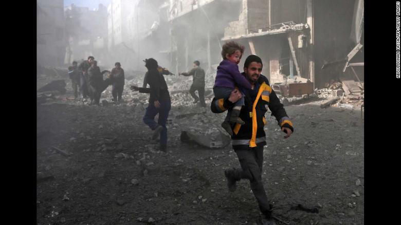 Un hombre lleva a un niño que rescató de los escombros en Hamouria.