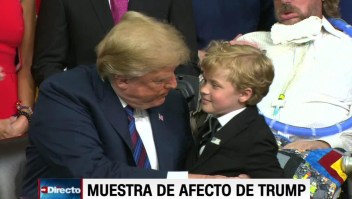 Un niño intenta abrazar a un distraído Trump