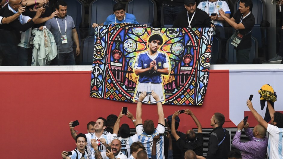 Diego Maradona asiste al encuentro entre Argentina y Nigeria con un póster de sí mismo dibujado como un santo. (Crédito: PAUL ELLIS/AFP/Getty Images)
