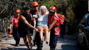 Miembros de los equipos de rescate llevan a una mujer herida en los incendios de Mati, en Grecia. (Crédito: AP Photo/Thanassis Stavrakis)