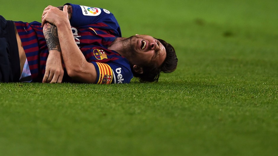 Messi hace gestos de dolor tras lesionarse el radio del brazo en el partido contra el Sevilla. (Crédito: Alex Caparros/Getty Images)