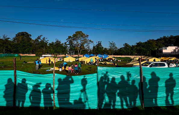 The shadow of journalists is casted against a canvas surrounding a camp for Venezuelan migrants as authorities start evicting the temporal shelter, in Bogota on January 15, 2019. - Venezuelan President Nicolas Maduro began a new term on January 10 that will keep him in power until 2025, with the economy in ruins and his regime more isolated than ever as neighbouring presidents shunned his inauguration after declaring his re-election illegitimate. (Photo by Juan BARRETO / AFP) (Photo credit should read JUAN BARRETO/AFP/Getty Images)