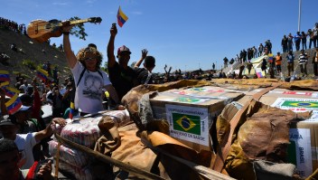 People cheer as trucks with humanitarian aid to Venezuela approach the Brazil-Venezuela border in Pacaraima, Roraima state, Brazil on February 23, 2019. - Venezuela braced for a showdown between the military and regime opponents at the Colombian border on Saturday, when self-declared acting president Juan Guaido has vowed humanitarian aid would enter his country despite a blockade. Early Saturday two large trucks -driven by Venezuelans and escorted by Brazilian police- carrying eight tonnes of emergency aid left Boa Vista in Brazil en route to the Venezuelan border. (Photo by Nelson Almeida / AFP) (Photo credit should read NELSON ALMEIDA/AFP/Getty Images)