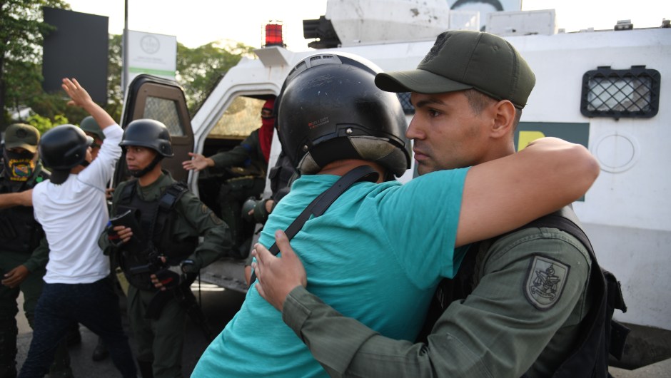 Un hombre abraza a un miembro de las fuerzas de seguridad en Caracas el 30 de abril de 2019. Crédito: YURI CORTEZ / AFP / Getty Images.