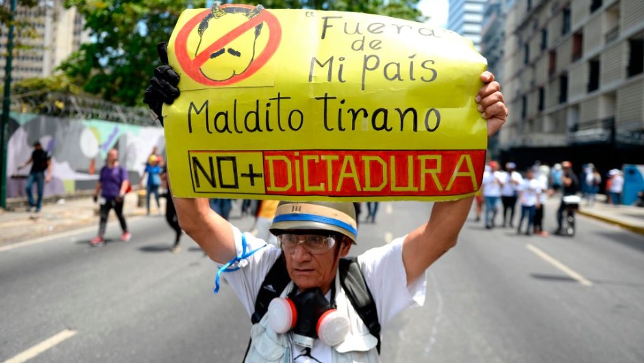 An opposition demonstrator holds a placard against Venezuelan President Nicolas Maduro as he takes part in a demonstration in Caracas to commemorate May Day on May 1, 2019 after a day of violent clashes on the streets of the capital spurred by opposition leader Juan Guaido's call on the military to rise up against Maduro. - Guaido called for a massive May Day protest to increase the pressure on President Maduro. (Photo by Matias DELACROIX / AFP) (Photo credit should read MATIAS DELACROIX/AFP/Getty Images)