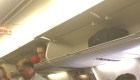 Auxiliar de vuelo trepa en compartimento de maletas