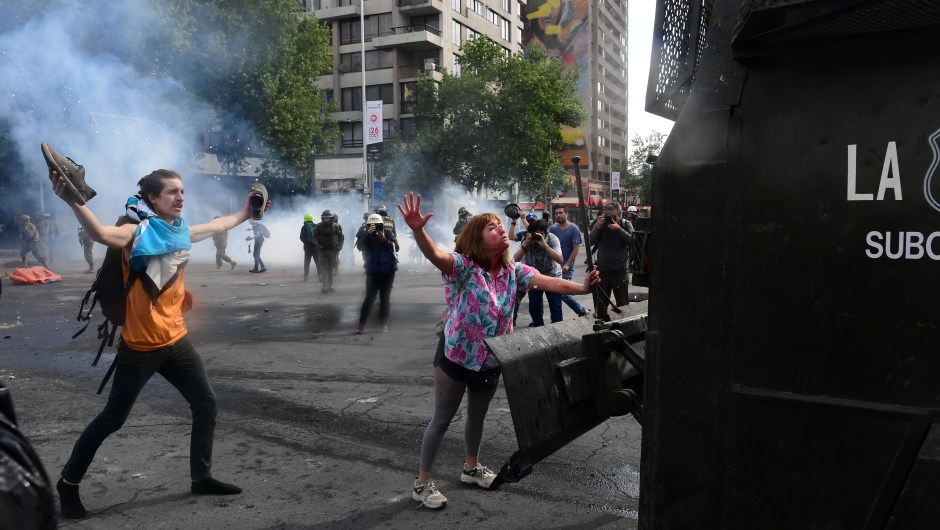 Demonstrators clash with riot police and army members in Santiago, on October 19, 2019. - Chile's president declared a state of emergency in Santiago Friday night and gave the military responsibility for security after a day of violent protests over an increase in the price of metro tickets. (Photo by Martin BERNETTI / AFP) (Photo by MARTIN BERNETTI/AFP via Getty Images)