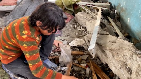 Niño reúne pedazos de los restos de su hermano después de que una bomba israelí estallara en una escuela en Gaza