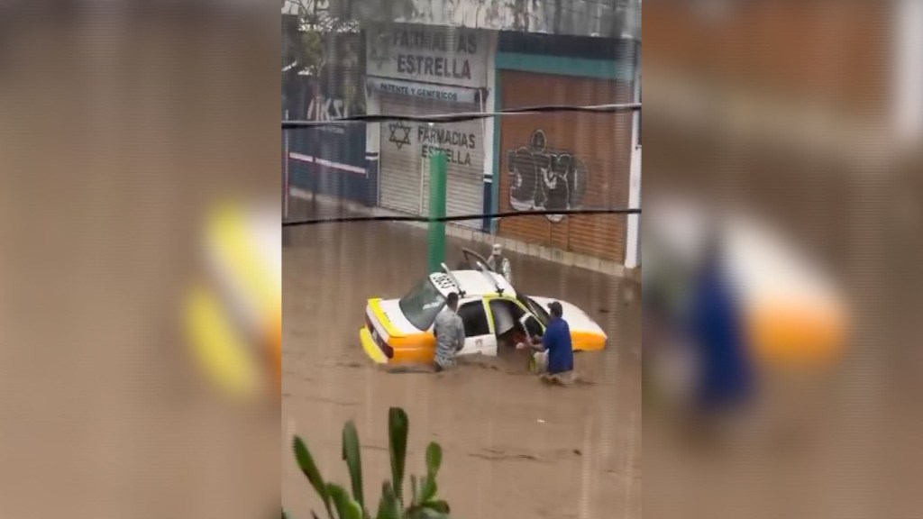 Fuerte corriente de agua arrastra a una persona y a un taxi con pasajeros en Acapulco después del paso de John